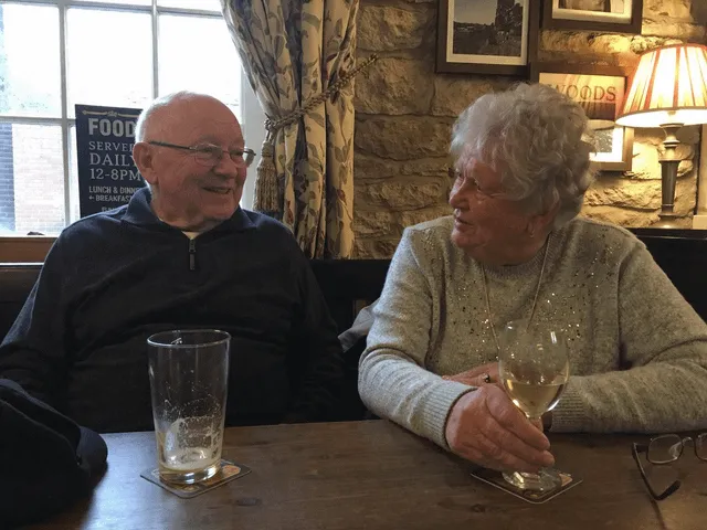 Промпт: "Amateur photograph of an elderly couple sat inside of a Yorkshire pub, amateur composition, candid"